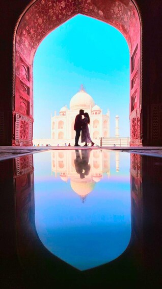 A couple kissing in front of the Taj Mahal with a reflection in the water. 1