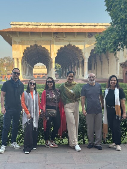 A group of people standing in front of a historical building with arches. 2