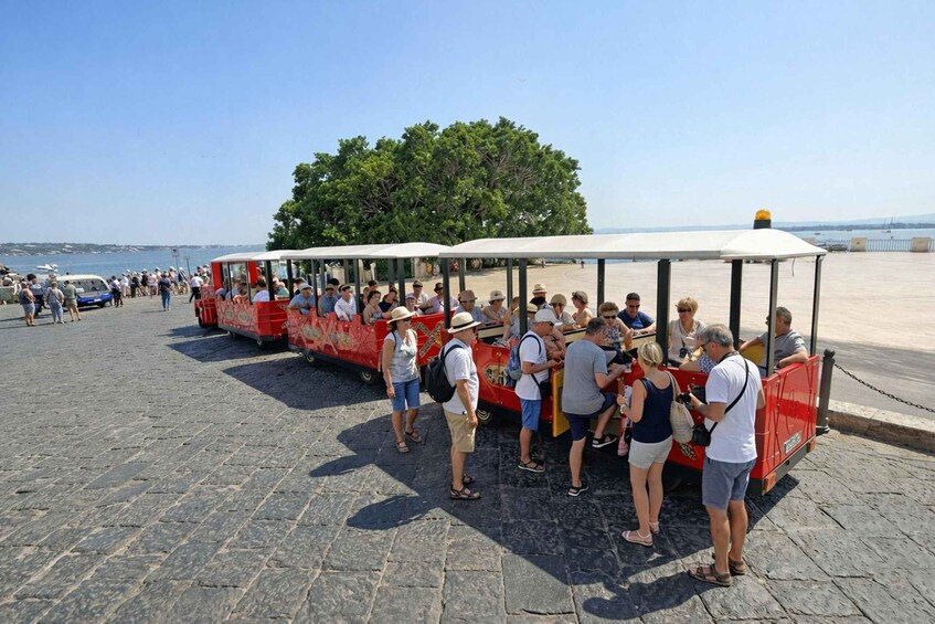 A red trolley with a canopy parked on a cobblestone path near a beach. 3