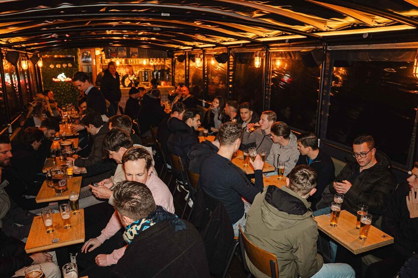 A crowded bar with people sitting at tables, holding drinks, and a bar area in the background. 5
