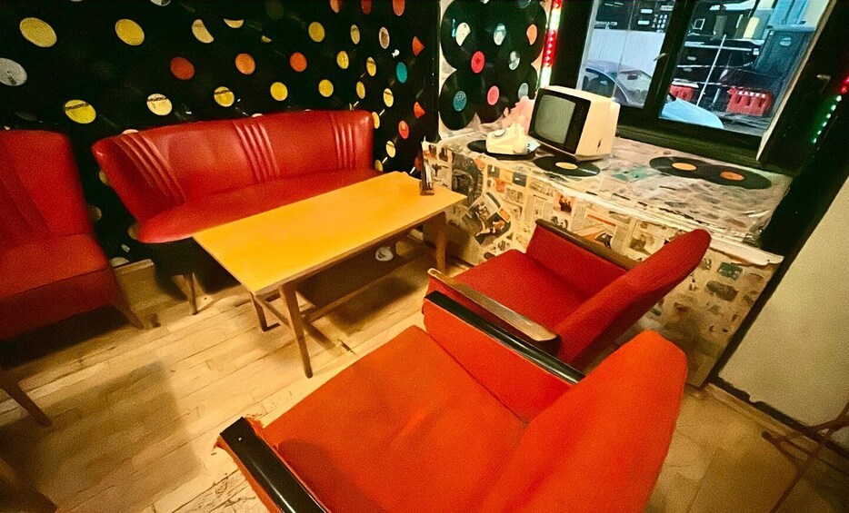 A retro diner with red booths, a yellow table, and a jukebox. 3
