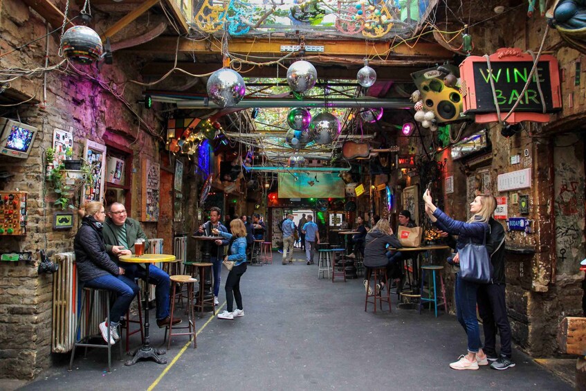 A lively bar with disco balls, a neon 'WINE BAR' sign, and patrons enjoying drinks. 1