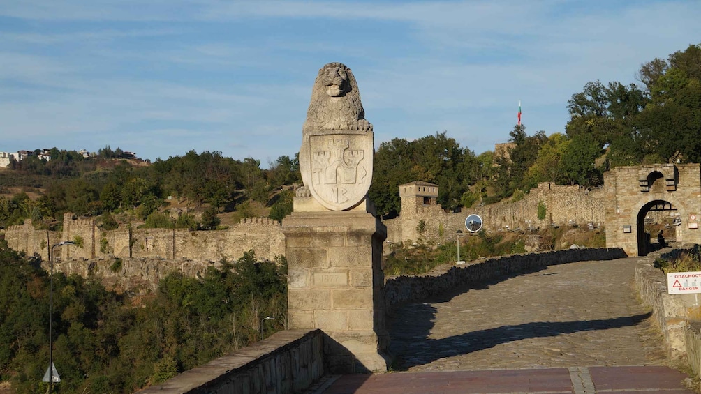 A stone monument with a lion's head and a shield, a stone bridge, and a sign with a warning symbol. 5