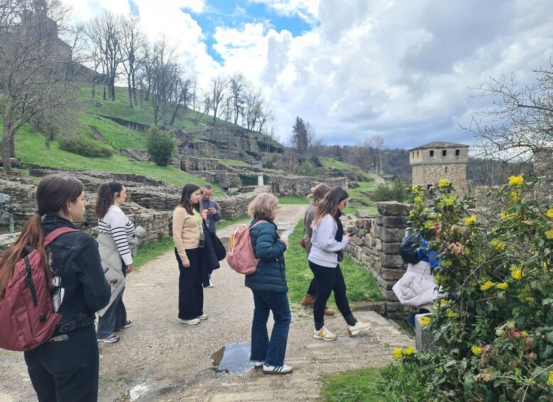 A group of people walking on a stone path in a historical site with ruins and greenery. 3