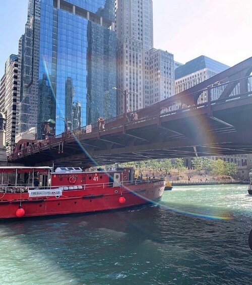 A red fireboat named 'Chicago Fire Boat 41' on a river with a city skyline and a bridge in the background. 2