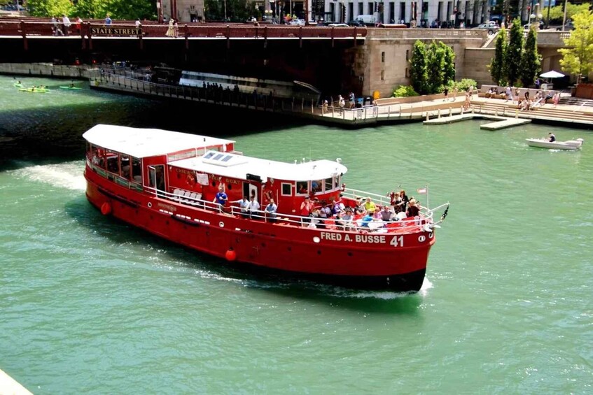 A red boat named 'Fred A. Busse 41' on a river with people on board and a bridge in the background. 5