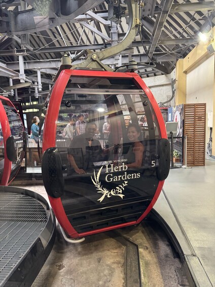 A red vehicle with a logo reading "KOBE NUNOBIKI Herb Gardens" parked inside a building. 2