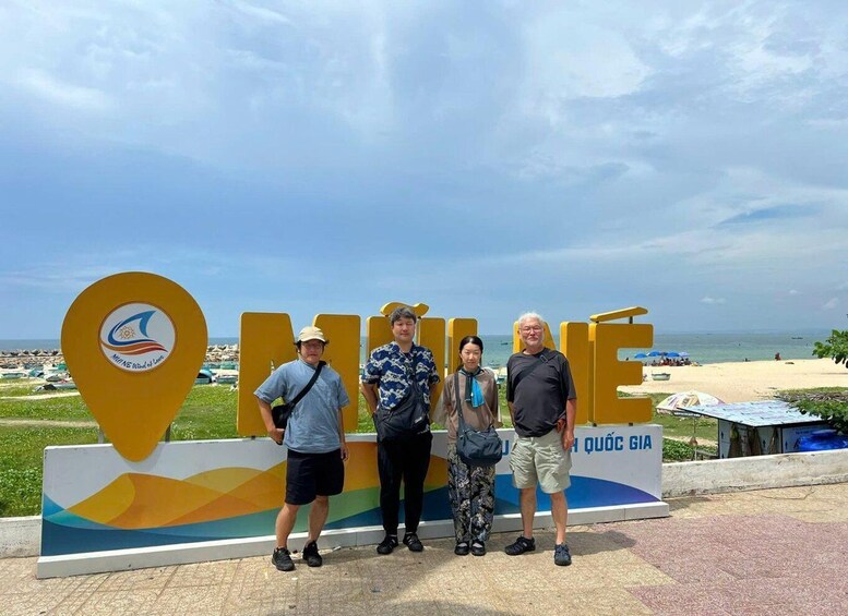 A group of people standing in front of a sign with a map pin and the word "MINE" on it. 4