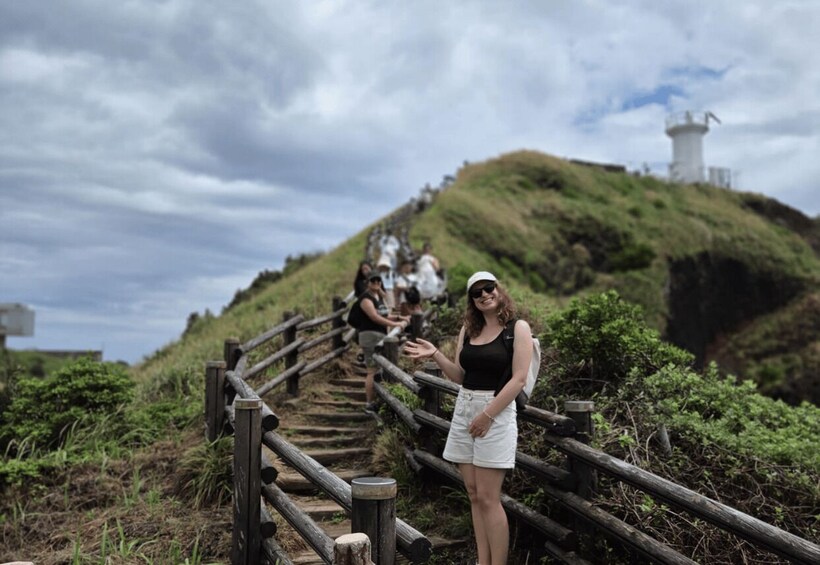 A person standing on a wooden staircase with a lighthouse in the background. 4