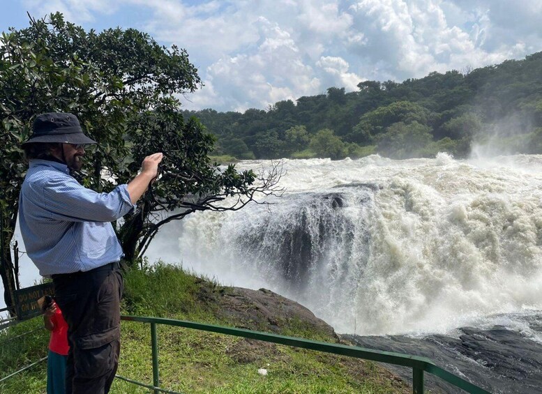 A man taking a photo of a powerful waterfall. 1