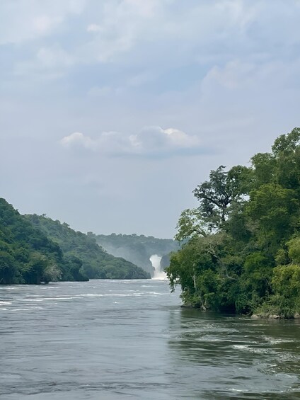 A river with a waterfall in the distance, surrounded by lush green hills. 2