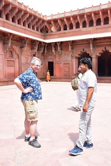 Two people standing in a courtyard with ornate architecture. 4