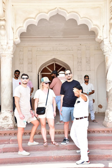 A group of people standing in front of a historic building with ornate arches and detailed carvings. 2