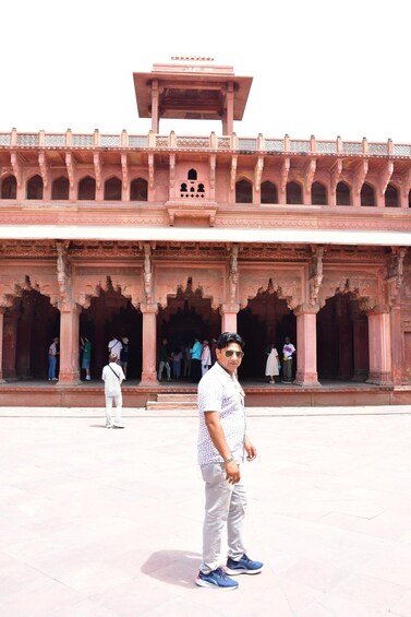 A man standing in front of a historic building with arches and columns. 5