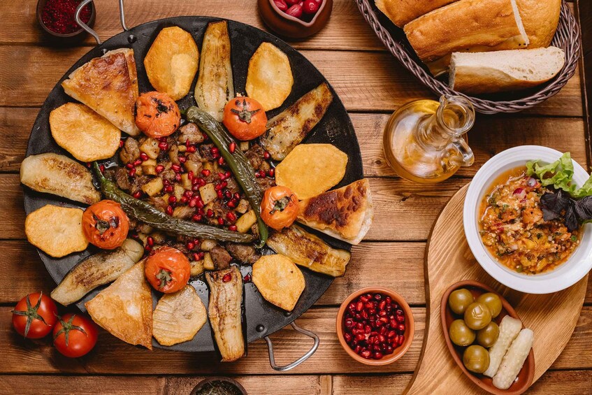 A variety of roasted vegetables and bread on a wooden table. 1