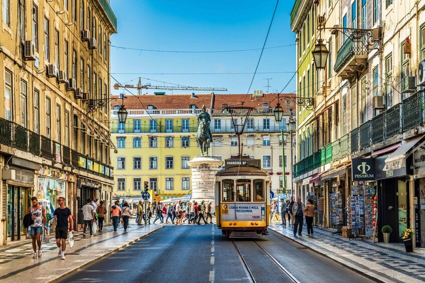 A tram moving down a street lined with colorful buildings and pedestrians. 3