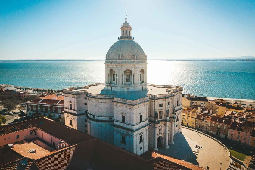 A coastal cityscape with a prominent white domed building, likely a cathedral, overlooking the sea. 4
