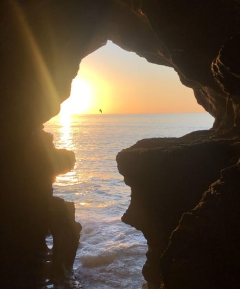 A sunset through a rock arch over the ocean. 1