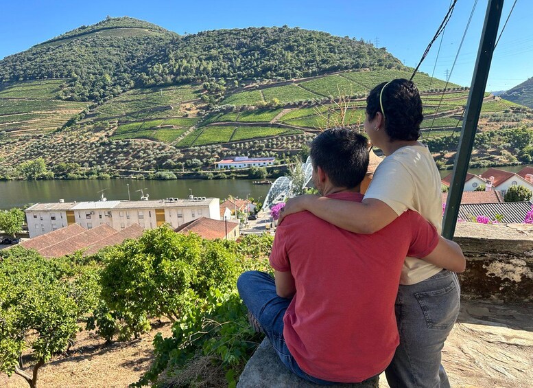 A couple overlooking a vineyard with a river and hills in the background. 4