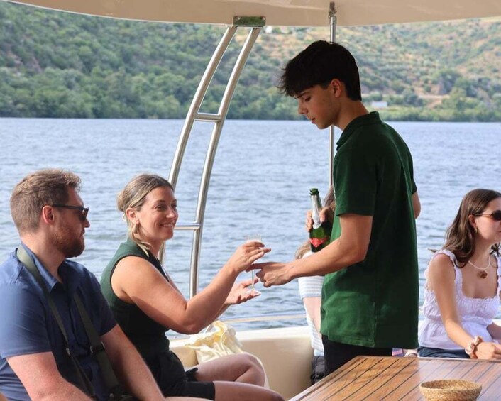 A group of people on a boat with a man pouring a drink. 4