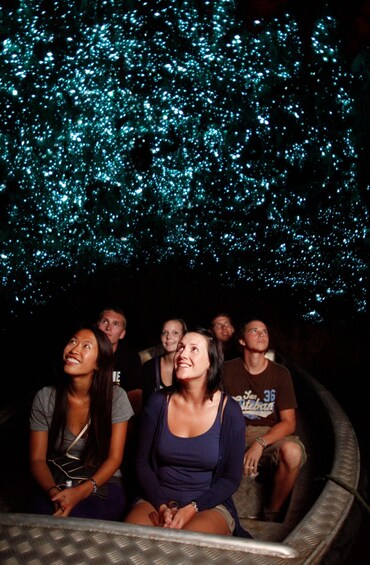 People seated in a circular arrangement, looking up at a ceiling with blue lights. 3