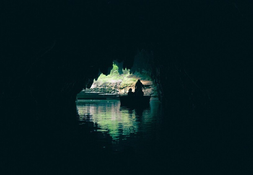 A cave with a boat and a person in the water. 5