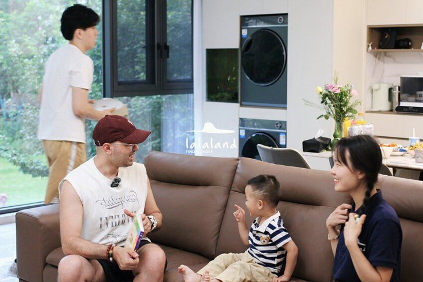 A family in a modern living room with a couch, a washing machine, and a dining area in the background. 4