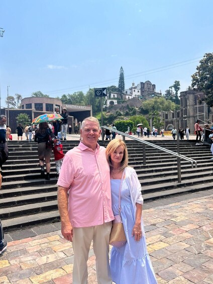 A couple standing on a stone staircase with a historic building in the background. 5