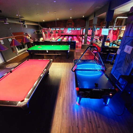A pool hall with multiple pool tables, including a brightly lit table with a blue backlight. 4