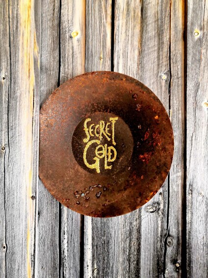 A rusty metal plate with the inscription "Secret God" on a wooden background. 5