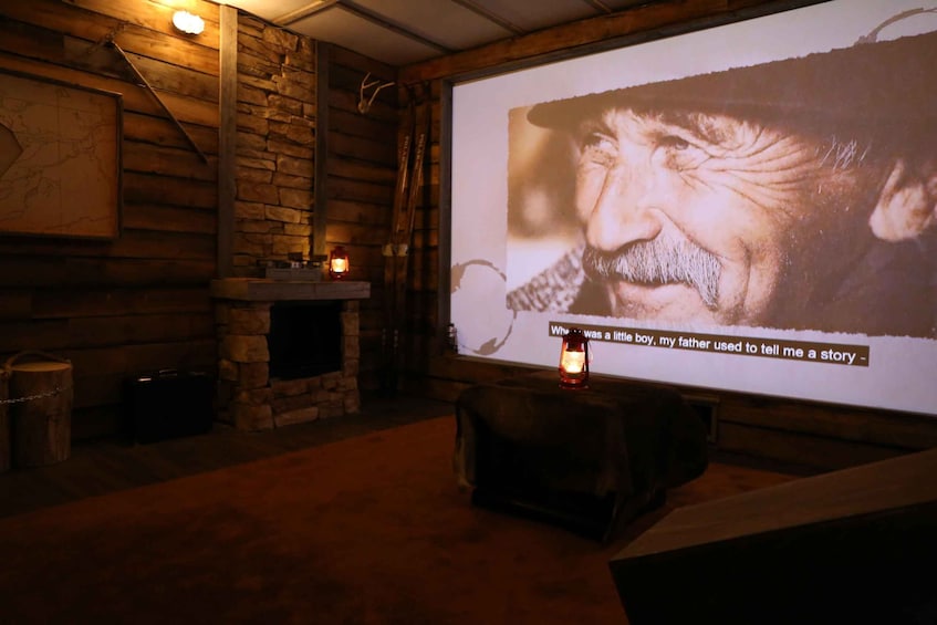 A cozy room with a fireplace, a map on the wall, and a projection screen displaying a story. 1