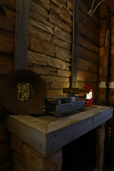 A rustic interior with a stone wall, a metal plate with 'SALT GAP' engraved, a lantern, and a small table. 3