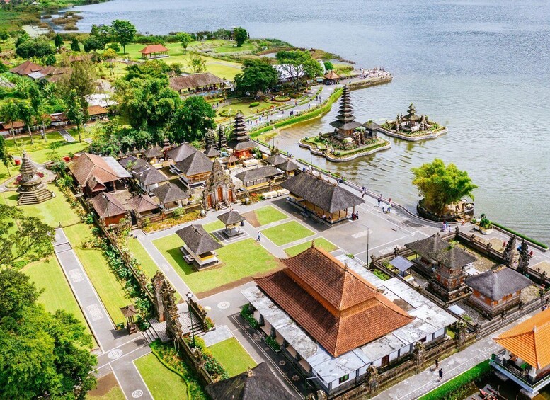 An aerial view of a temple complex with a large central building, smaller structures, and a surrounding garden by a lake. 3