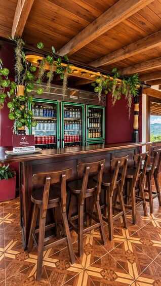 A bar with wooden chairs and a green refrigerator stocked with beverages. 3