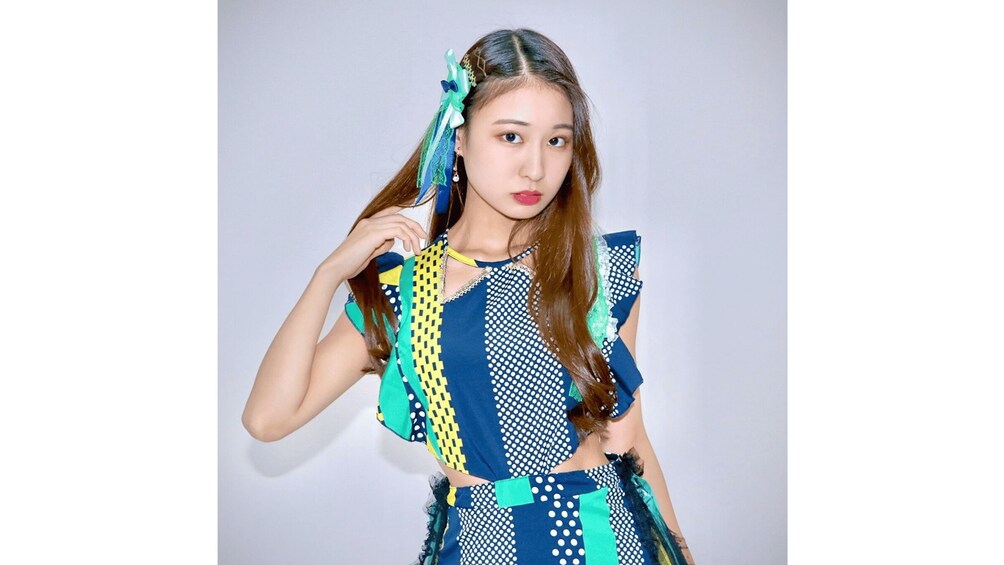 A person wearing a patterned dress with blue, yellow, and white colors. 2