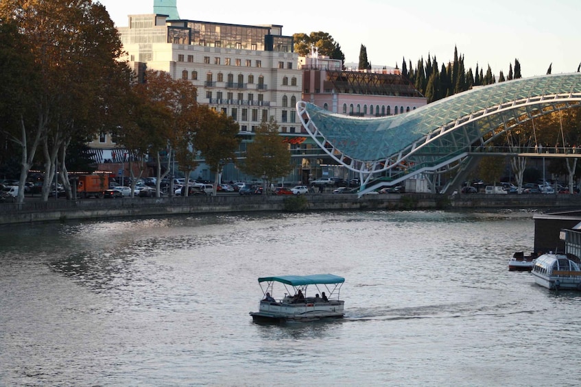 A boat with a blue canopy on a river, surrounded by buildings and trees. 4