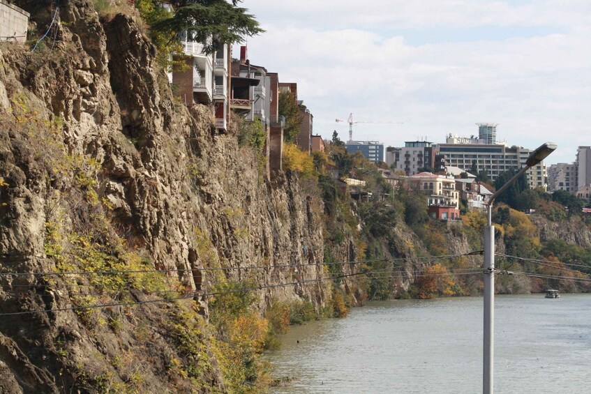 A rocky riverbank with buildings and a bridge. 2