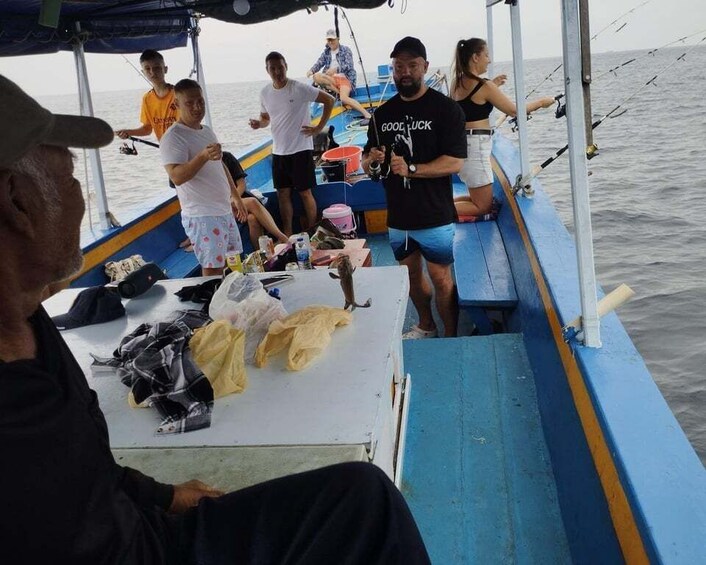 A group of people on a boat with fishing rods, some standing and some seated, in a body of water. 5