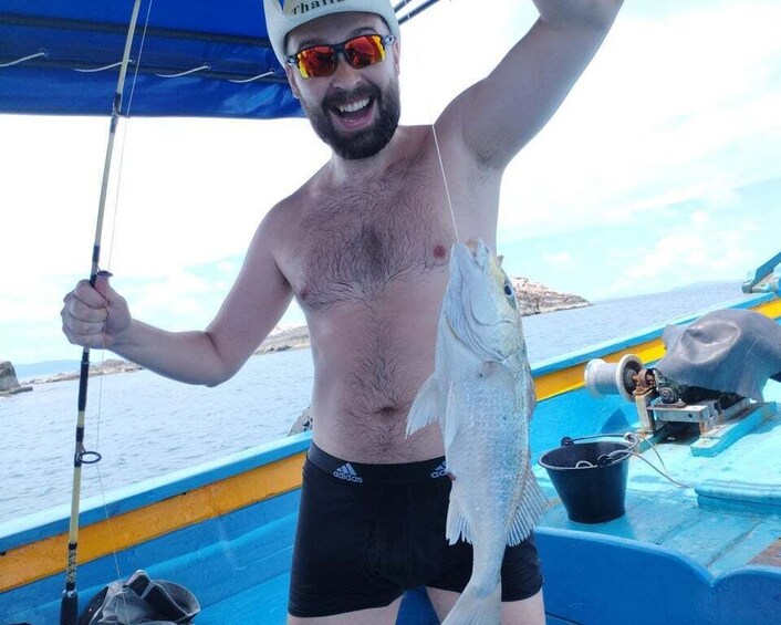 A man holding a fish on a boat. 3