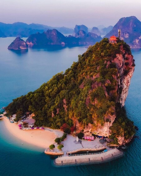 A coastal landscape with a prominent cliff, a beach, and a small red-roofed structure on top of the cliff. 2