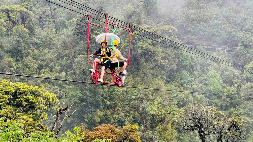 A person on a suspended red bicycle in a forested area. 3