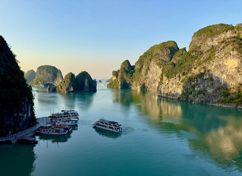 A calm river with boats docked on the left, surrounded by lush green cliffs. 3