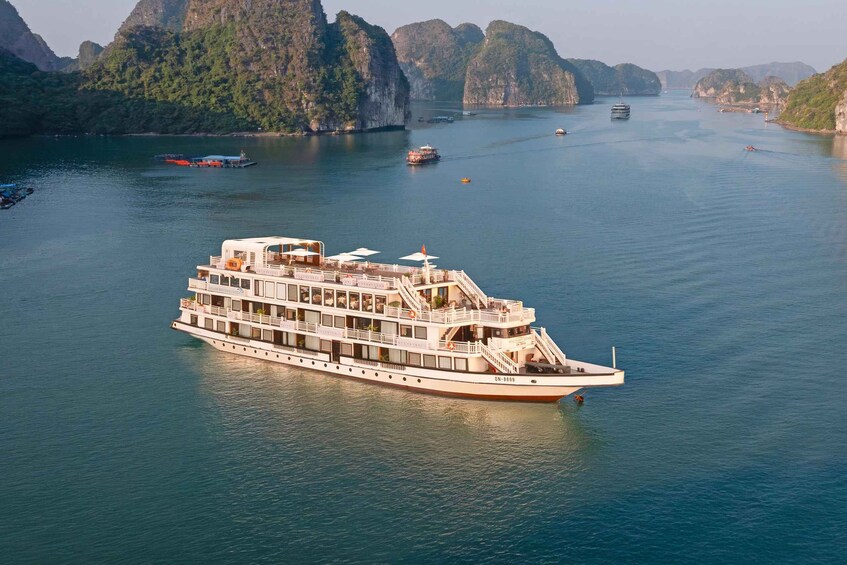 A large white river cruise ship with multiple decks and a flag, navigating through a calm river surrounded by steep, forested cliffs. 1