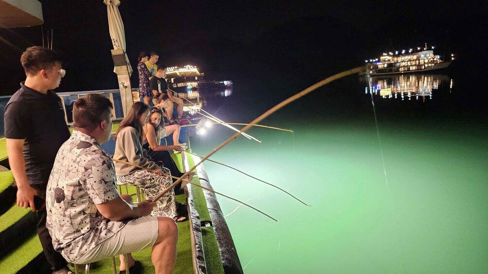 People fishing at night on a boat with a cityscape in the background. 5