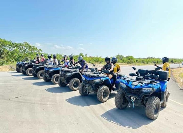 A group of people riding blue ATVs on a paved road. 1