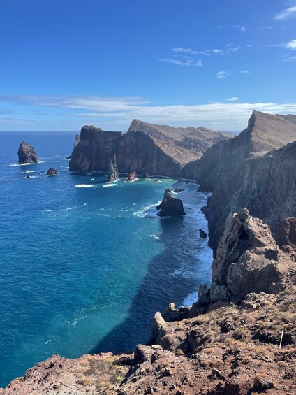 A coastal landscape with rocky cliffs and clear blue waters. 2