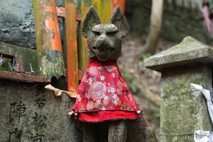 A stone statue with a red cloth, surrounded by stone structures and bamboo poles. 2
