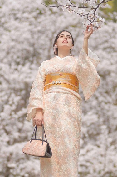 A person in traditional attire holding a branch of cherry blossoms. 1