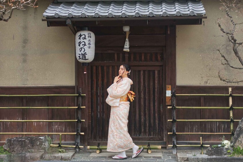 A person in traditional attire standing in front of a wooden building with a sign. 3