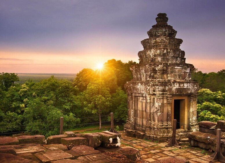 A temple with a central tower, surrounded by lush greenery and a sunset in the background. 5